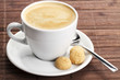 kaffee in einer weissen tasse mit einem löffel und amarettini