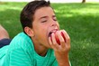 boy teenager eating red apple on garden grass boy teenager eating red apple on garden grass