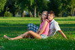 Two young lovers sitting on the lawn in the park and looks into Two young lovers sitting on the lawn in the park and looks into