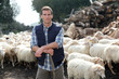 Foto: Shepherd standing by sheep in meadow Shepherd standing by sheep in meadow