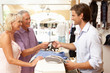 Photo: Male Sales Assistant At Checkout Of Clothing Store With Customer Male Sales Assistant At Checkout Of Clothing Store With Customer