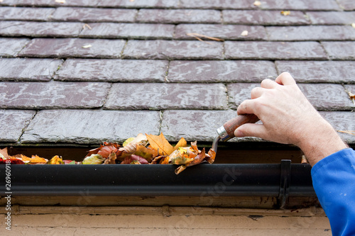 Photo: Clearing Autumn Leaves from Gutter with Trowel Clearing Autumn Leaves from Gutter with Trowel