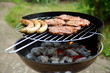 Grill mit Grillfleisch und Bratwurst im Garten