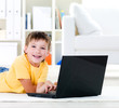 Happy preschooler with laptop at home