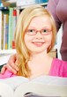 A cute little schoolgirl in library with teacher