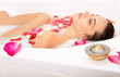 Attractive naked girl enjoys a bath with milk and rose petals