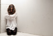 Young insane woman with straitjacket on knees looking at camera