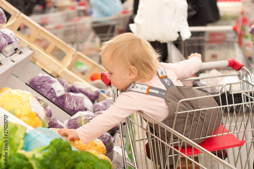 Photo: toddler girl sit in shopping cart in supermarket toddler girl sit in shopping cart in supermarket