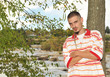 Attractive Latino man leaning against a tree outside.