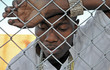 Young depressed African American man behind a chain link fence. Young depressed African American man behind a chain link fence.
