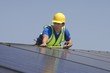 Maintenance worker measures solar array on rooftop, Los Angeles, California