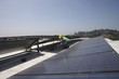 Maintenance worker checks solar array on rooftop in Los Angeles, California