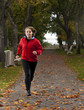 Beautiful female athlete running in park on autumn day.