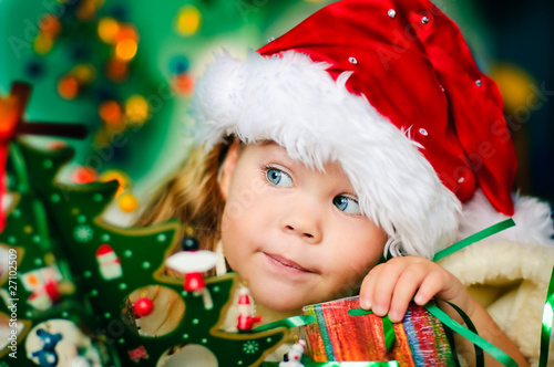 Photo: Happy small girl in santa hat have a christmas Happy small girl in santa hat have a christmas