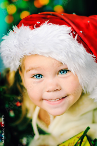 Foto: portrait of little happy Christmas girl in santa's hat portrait of little happy Christmas girl in santa's hat