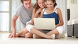 Happy teenage friends in playful mood at home while using laptop