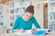 pretty young college student in a library (shallow DOF; color to