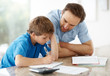 Young man assisting to his little son in schoolwork