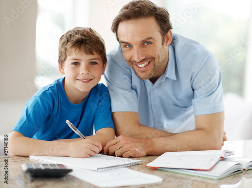 Photo: Smiling young father helping to his son doing homework Smiling young father helping to his son doing homework