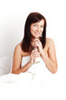 Photo: Young beautiful woman drinking milk sitting on white bed Young beautiful woman drinking milk sitting on white bed