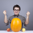 The young mad men try to eat two apples and pumpkin.