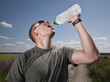 Foto: Male athlete drinking water on hot summer day. Male athlete drinking water on hot summer day.