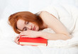 young woman with red book in white bedding young woman with red book in white bedding