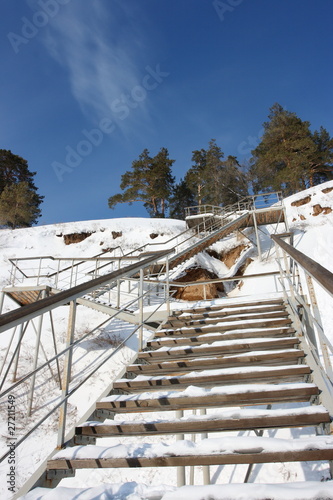 Photo: Stairs with landing against a snow slope against pines Stairs with landing against a snow slope against pines
