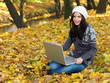 Foto: Beautiful woman working on laptop in park during autumn season Beautiful woman working on laptop in park during autumn season