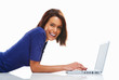 Happy young female student casually lying on floor with a laptop