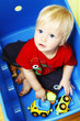 Little boy seating in blue box and playing with toys