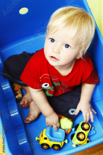 Photo: Little boy seating in blue box and playing with toys Little boy seating in blue box and playing with toys