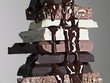 close up of chocolate syrup dripping over stack of chocolate bars
