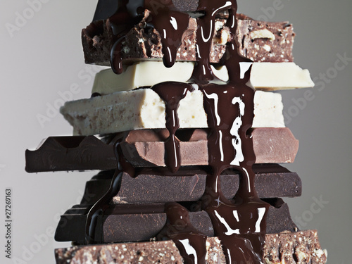 Photo: close up of chocolate syrup dripping over stack of chocolate bars close up of chocolate syrup dripping over stack of chocolate bars