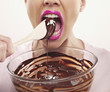 woman with pink lipstick biting wooden spoon with chocolate batter