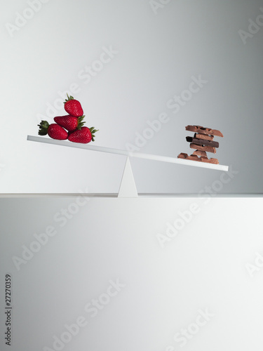 Photo: chocolate bars tipping seesaw with strawberries on opposite end chocolate bars tipping seesaw with strawberries on opposite end