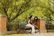 Two Young Women Sitting On Park Bench