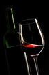glass of red wine with a bottle and black background
