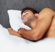 Shirtless young man sleeping in his bed