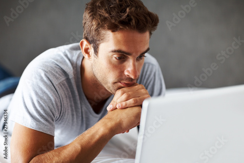 Photo: Confident young guy using laptop Confident young guy using laptop