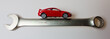 a small red car on a steel wrench a small red car on a steel wrench