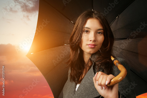 Foto: Female with black umbrella on beautiful sunset background Female with black umbrella on beautiful sunset background