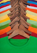 Many vibrant t-shirts on wooden hangers Many vibrant t-shirts on wooden hangers