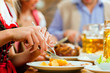 Leute essen Schweinebraten in Restaurant
