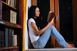 pretty woman is sitting on window and reading book