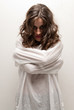 Young insane woman with straitjacket standing looking at camera