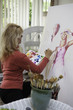 beautiful blond artist in her fifties painting on canvas