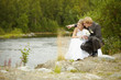 Bride and groom sit on riverbank