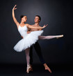 Two graceful ballet dancers performing against black background