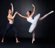 Two graceful ballet dancers performing against black background